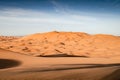 Tall dunes of Erg Chebbi. Desert landscape in Morocco. Orange sand dunes during sunrise wiht blue sky