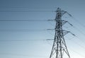Tall electricity pylon with multiple high voltage cables silhouetted against a blue sky