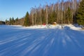 Tall forest trees on the banks of a frozen snow-covered river. Winter sunny landscape. Royalty Free Stock Photo