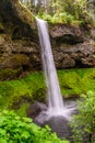 Tall Forest Waterfall with people walking underneath. Royalty Free Stock Photo