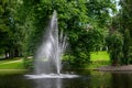 Tall fountain in the middle of a pond in a green park, as a nature background Royalty Free Stock Photo
