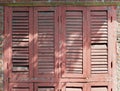 old rose color wooden window with louver panel that peeling and damaged under sunlight