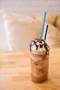 Tall glass of delicious cold iced coffee float or milkshake topped with ice cream or cream on a rustic wooden counter for Royalty Free Stock Photo