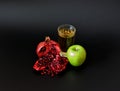 A tall glass of fresh tropical fruit juice on a black background, next to pieces of a pomegranate fruit and a ripe green apple Royalty Free Stock Photo