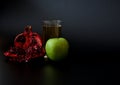 A tall glass of fruit juice on a black background, next to a green apple and a broken ripe pomegranate fruit with seeds Royalty Free Stock Photo