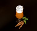 A tall glass of light wheat beer with high white foam, ears and ripe hops on a black background Royalty Free Stock Photo