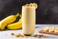 a tall glass of smoothie with banana slice and walnut toppings