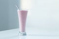 Tall glass with strawberry smoothie and stainless steel straw set in natural light Royalty Free Stock Photo