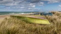 Tall grass at the beach, Green and blue boats lying in the grass with the bottom up. The sea in the background. blue sky with Royalty Free Stock Photo