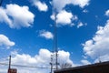 A tall gray radio tower surrounded by brown and bare winter trees with blue sky and clouds in Douglasville