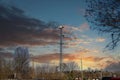 A tall gray radio tower surrounded by brown and bare winter trees with blue sky and powerful clouds at sunset in Douglasville