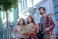 Tall guy and two girls with map exploring sights of city Royalty Free Stock Photo