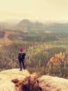 Tall hiker man with red cap, poles in hand and with big backpack stand on rock. Misty spring Royalty Free Stock Photo