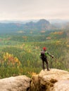 Tall hiker man with red cap, poles in hand and with big backpack stand on rock. Misty spring Royalty Free Stock Photo