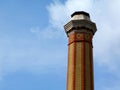 Tall industrial chimney stack of yellow and red brick of octagonal base Royalty Free Stock Photo