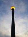 Tall lamppost against a twilight sky with fluffy clouds