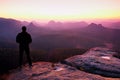 Tall man in black on cliff and watch to mountain sunrise.Silhouette in selfconfident pose Royalty Free Stock Photo