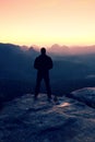 Tall man in black on cliff and watch to mountain sunrise.Silhouette in selfconfident pose Royalty Free Stock Photo