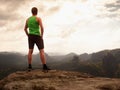 Tall man enjoy freedom on peak of mountain edge. Alone tourist watching over misty valley