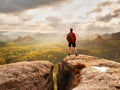 Tall man enjoy freedom on peak of mountain edge. Alone tourist watching over misty valley