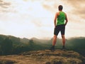 Tall man enjoy freedom on peak of mountain edge. Alone tourist watching over misty valley