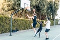 Tall man jumping to throw a ball into a basket while playing basketball with friends Royalty Free Stock Photo