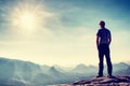 Tall man in outdoor clothes stands alone on the peak of rock. Royalty Free Stock Photo