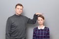 Tall man is showing height of short woman, people of different heights Royalty Free Stock Photo