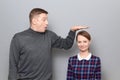 Tall man is showing height of short woman, people of different heights Royalty Free Stock Photo