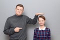 Tall man is showing height of short woman and pointing at her Royalty Free Stock Photo