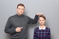 Tall man is showing height of short woman and pointing at her Royalty Free Stock Photo