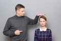 Tall man is showing height of short woman and pointing at her Royalty Free Stock Photo