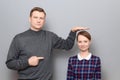 Tall man is showing height of short woman and pointing at her Royalty Free Stock Photo