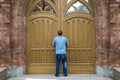 A tall man stands in front of the huge wooden doors Royalty Free Stock Photo