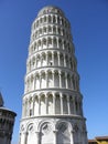 Tall marble Leaning Tower of Pisa with arches, doors and pillars on all levels of structure. Royalty Free Stock Photo