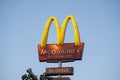 A tall Mc Donald\'s sign against a bright blue sky Royalty Free Stock Photo