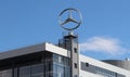 A tall Mercedes-Benz sign with the recognizable brand emblem stands