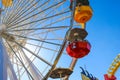 A tall metal Ferris wheel with colorful cars around the wheel on with blue sky the Santa Monica Pier