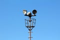 Tall metal pole with stairs leading to high; platform with three large electrical reflector lights