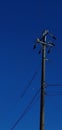 Tall, metal telephone pole stands in the center of the frame with many wires connected to it