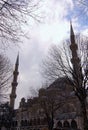 Tall minarets against colorful vibrant sky. Winter landscape view of Sultan Ahmed Mosque. Trees without leaves in the foreground. Royalty Free Stock Photo