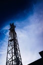 A tall modern communications tower provides telecommunications service to a city, negative space on blue background