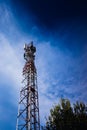 A tall modern communications tower provides telecommunications service to a city, negative space on blue background