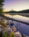 Tall obelisk monument on a mountain reflecting in still water at sunrise. High Point State Park, NJ
