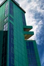 A tall office building in green against a blue sky and white clouds. Royalty Free Stock Photo