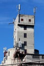 Tall old dilapidated concrete rarely used industrial building with densely mounted cell phone antennas and transmitters on top