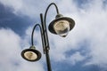 Tall old lampost with two functional bulbs. The other one is not covered and the post is painted with dark green hue. Its backgrou Royalty Free Stock Photo