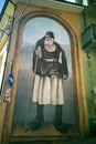 Tall old man painting located on house facade under Museo lettering. Snapshot from Fonni town streets, Sardinia, Italy