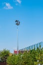 Tall pillar with spotlights to illuminate a football stadium against the sky with clouds and protective mesh Royalty Free Stock Photo