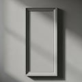 A tall rectangular mirror with a subtle frame casts a shadow on a plain wall isolated on white background Royalty Free Stock Photo